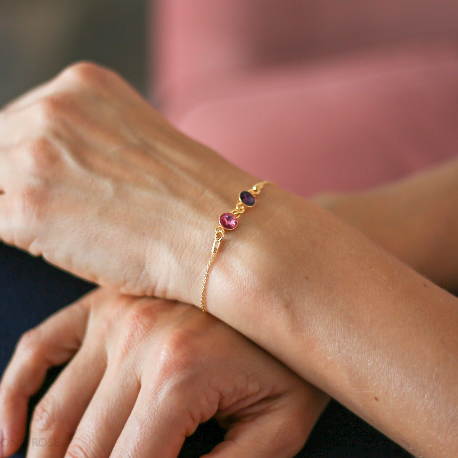 Gold bracelet with three colored stones on a wrist
