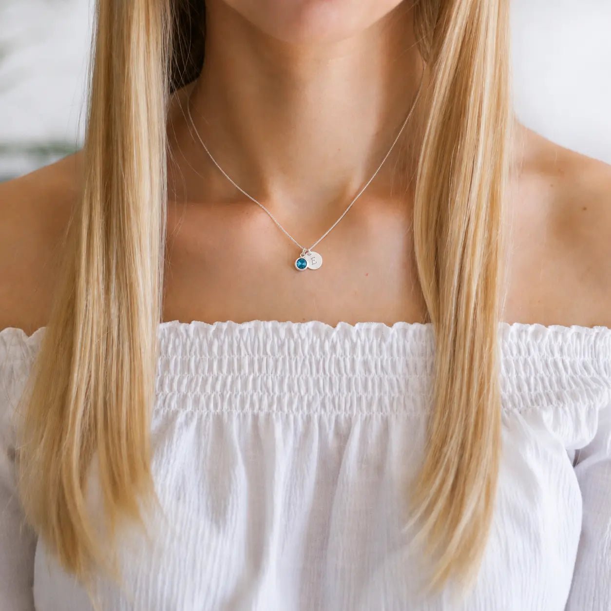 Person wearing a personalised birthday necklace with a white top