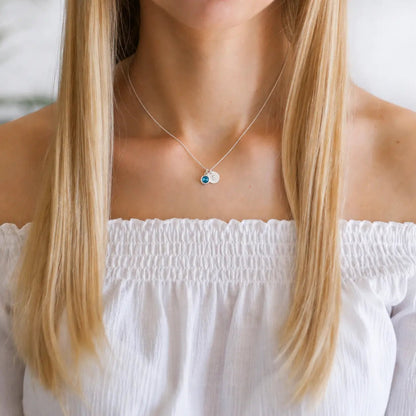 Person wearing a personalised birthday necklace with a white top