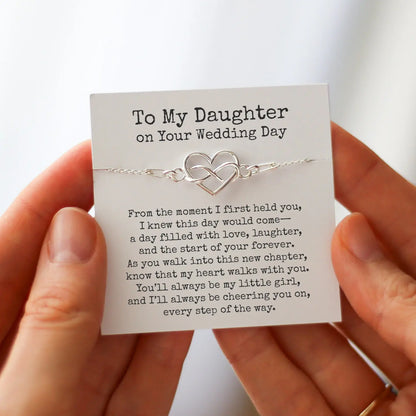 Silver heart infinity bracelet on a “To My Daughter on Your Wedding Day” message card, a meaningful daughter wedding gift held in two hands.